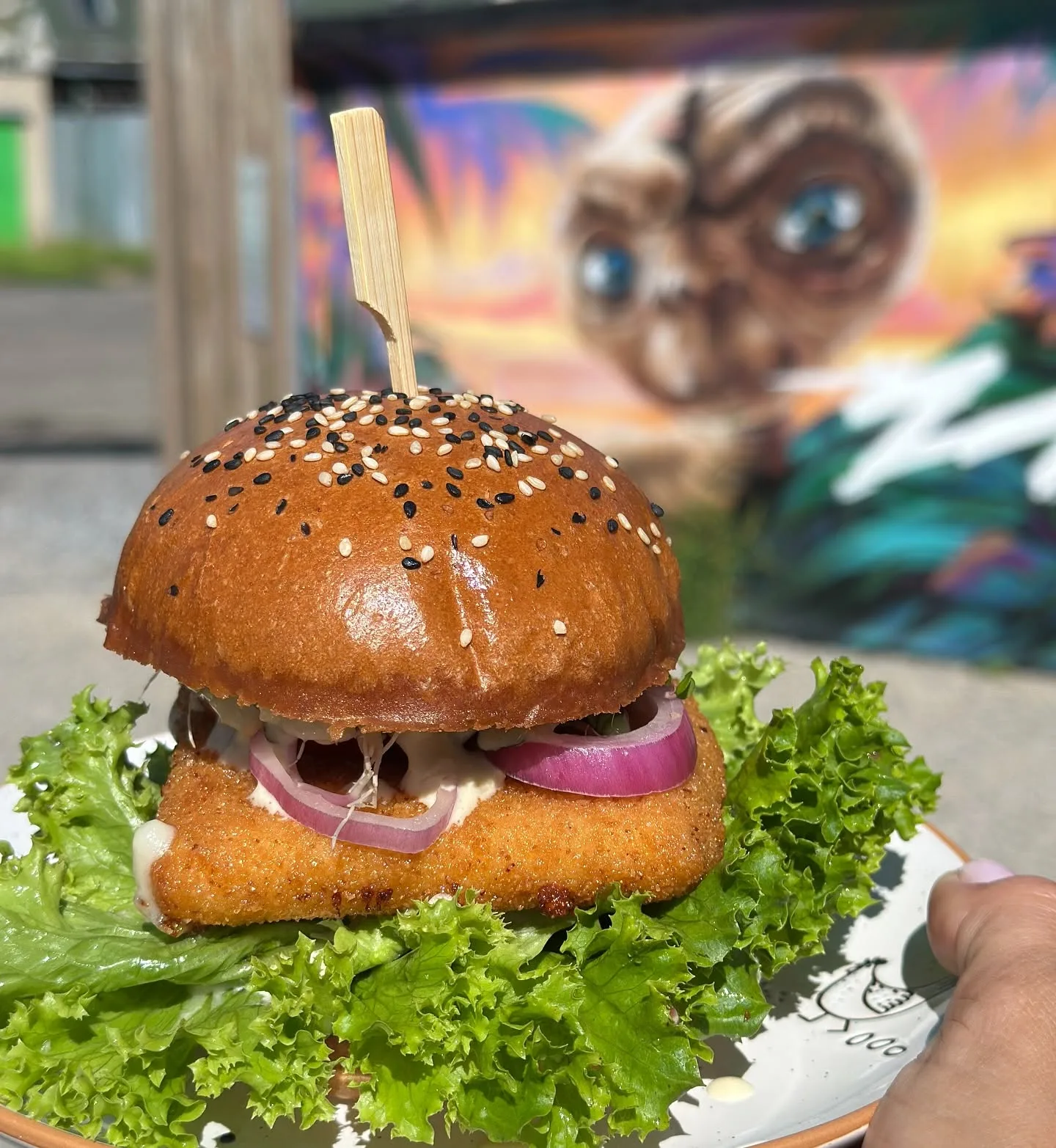 Smažák v bulce, v pozadí mural s E.T.
