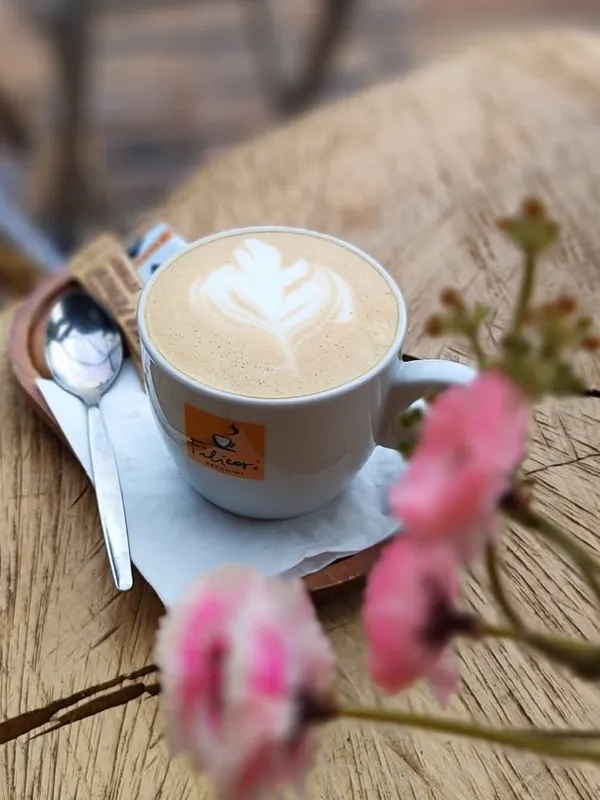 Cappuccino s latte art na stole z dřevěného plátu